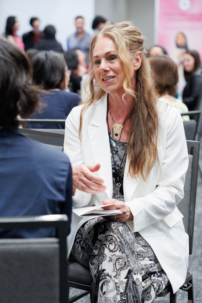 An attendee in a white blazer mid-conversation at her table