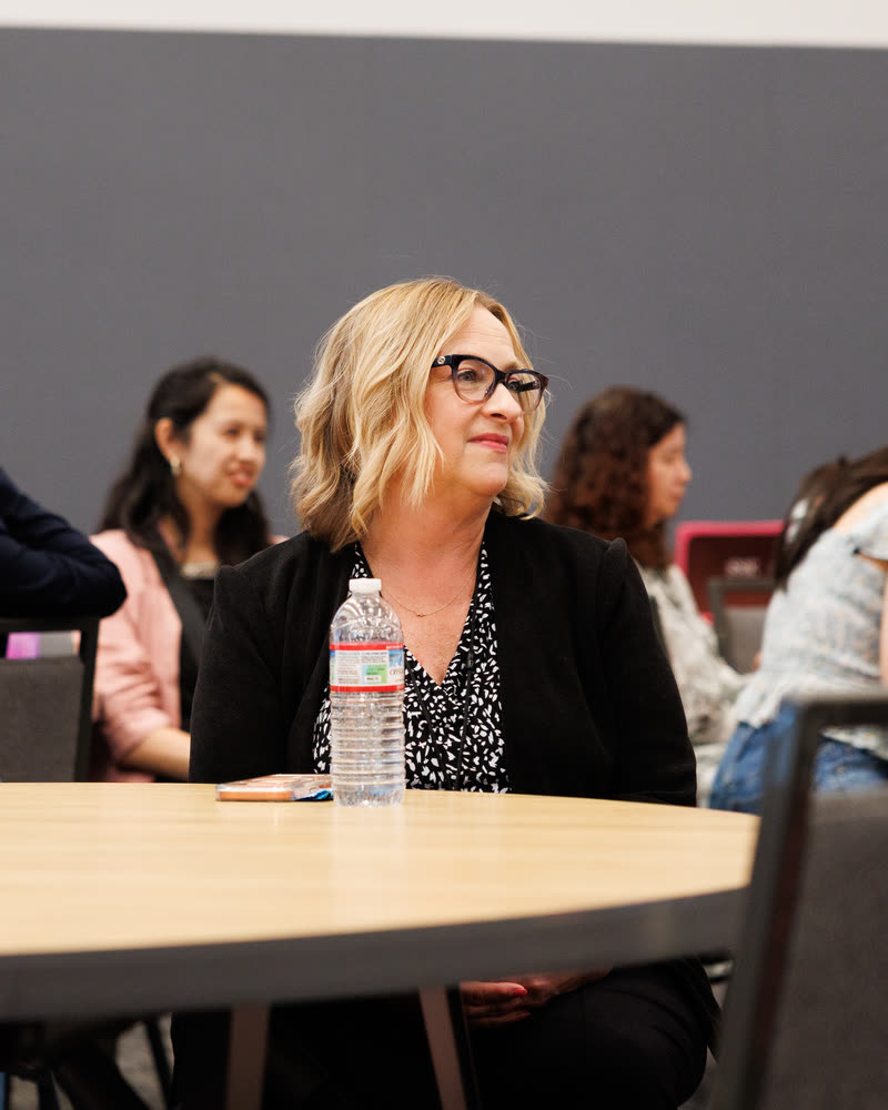 An attendee in glasses smiling as she listens at a round table