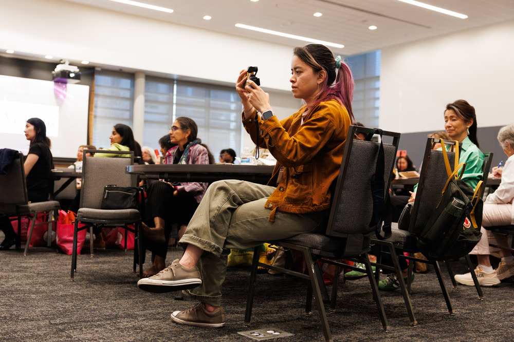 An attendee taking a photo of the speaker from her seat
