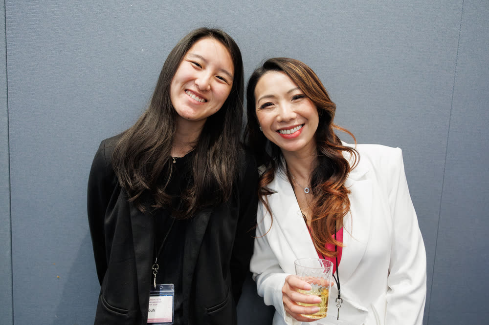 Two attendees with name badges smiling for a photo