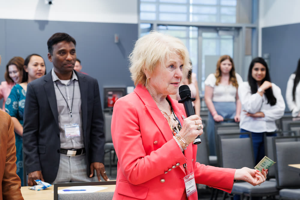An attendee in a red blazer asking a question into a handheld mic
