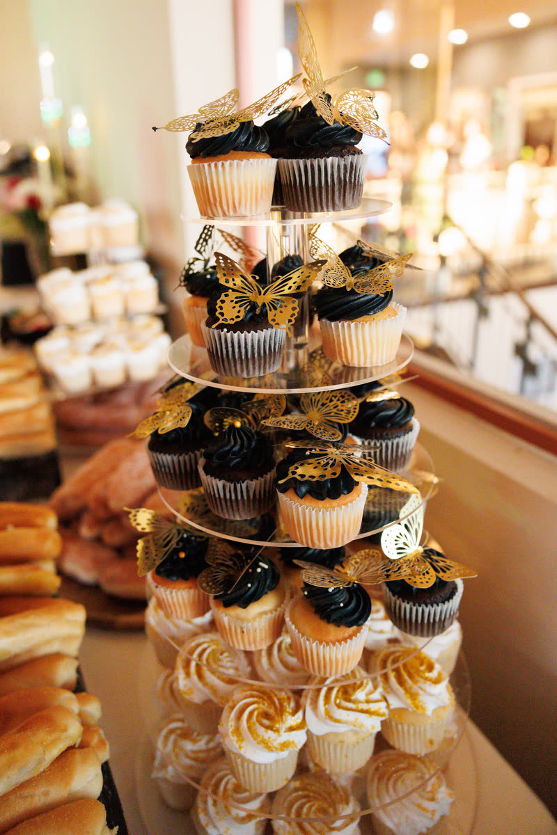 A tower of black and gold cupcakes on the dessert table