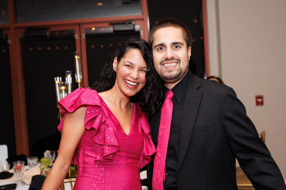 A couple in pink and black smiling at the reception