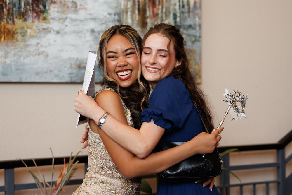 The debutante hugging a friend in the hallway