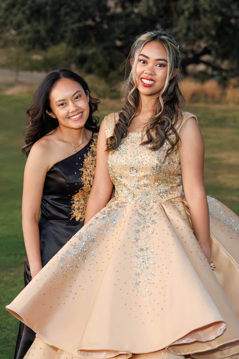 Two sisters in gowns posing together on the lawn