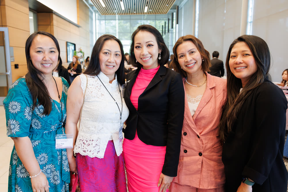 Five women in colorful outfits posing together at a conference