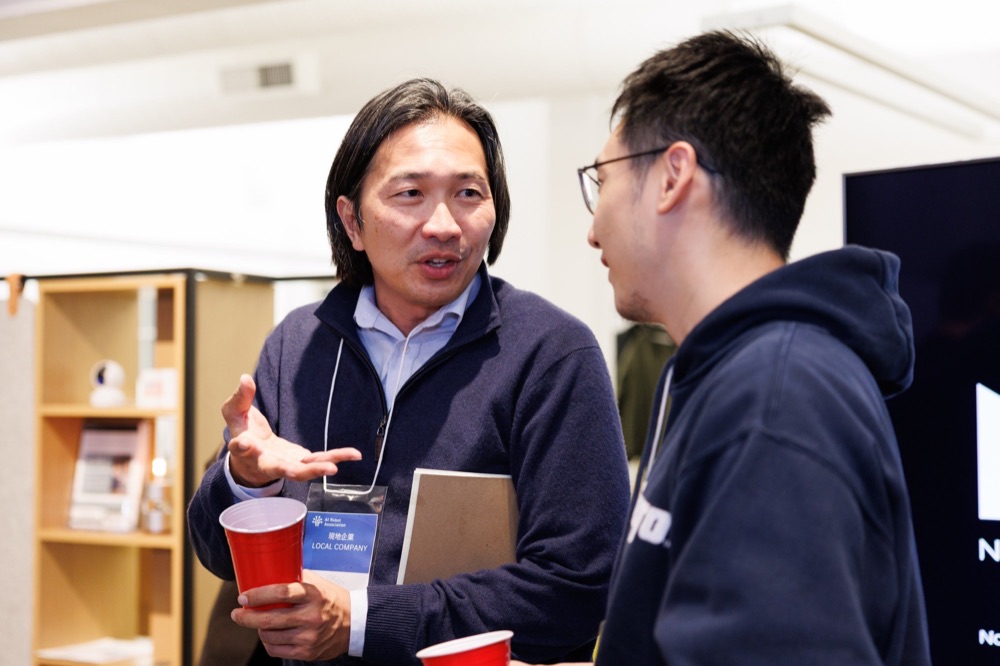 Two men in conversation, one holding a notebook