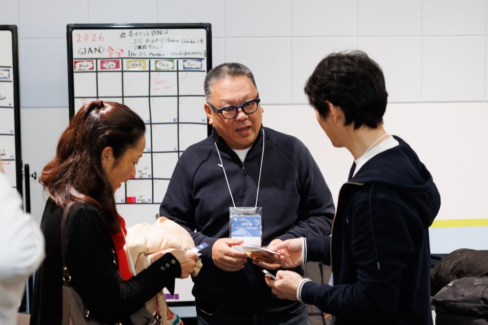 Three attendees talking in front of a whiteboard calendar