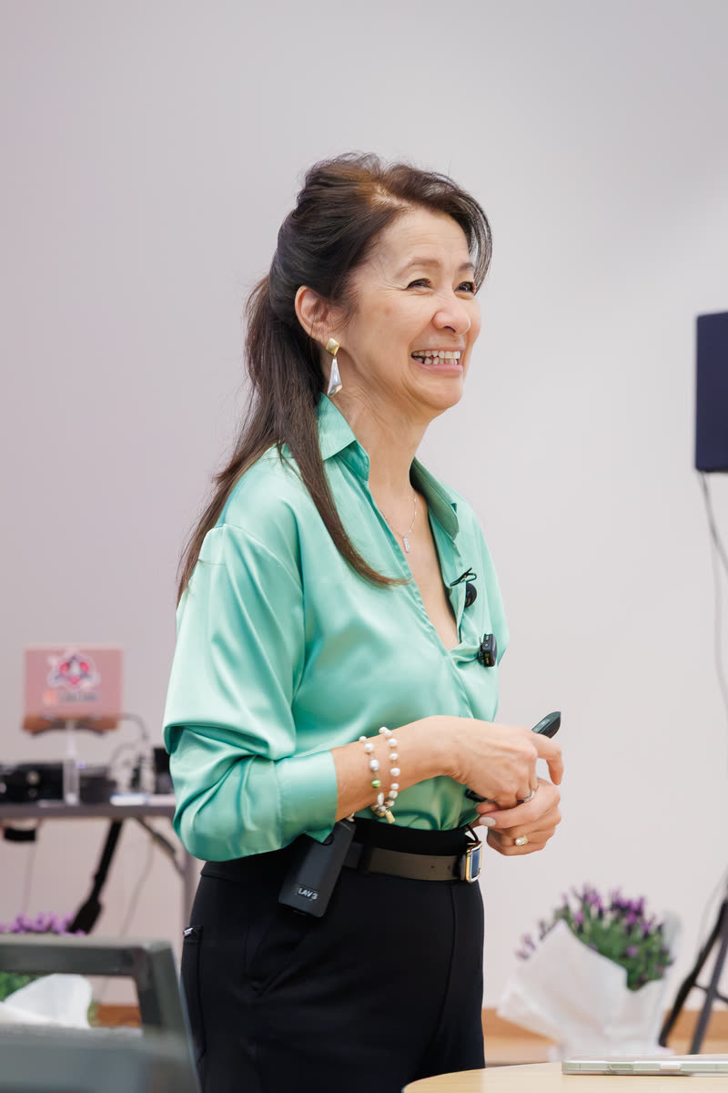 A speaker in a green blouse smiling as she talks to the room