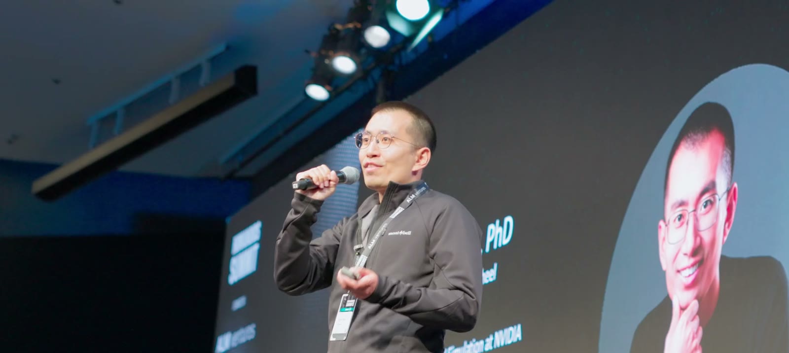 A keynote speaker on stage at the Humanoids Summit, lit by stage lights